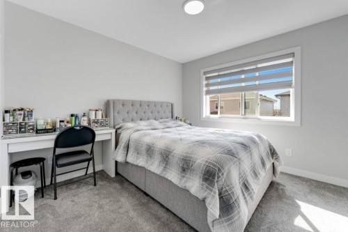 This room features soft gray carpeting, a large window with horizontal blinds, and a built-in ceiling light fixture - 452 Roberts Crescent, Leduc, AB - Indoor Photo Showing Bedroom
