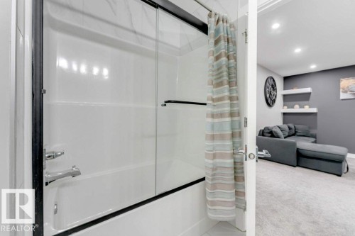 The bathroom features a white bathtub with a chrome faucet and a clear glass sliding shower door - 452 Roberts Crescent, Leduc, AB - Indoor Photo Showing Bathroom