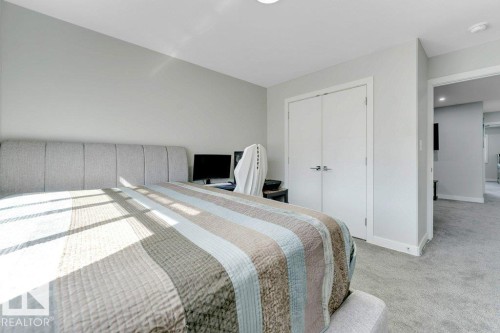 This room features light gray carpeting, neutral wall colors, and white double closet doors - 452 Roberts Crescent, Leduc, AB - Indoor Photo Showing Bedroom