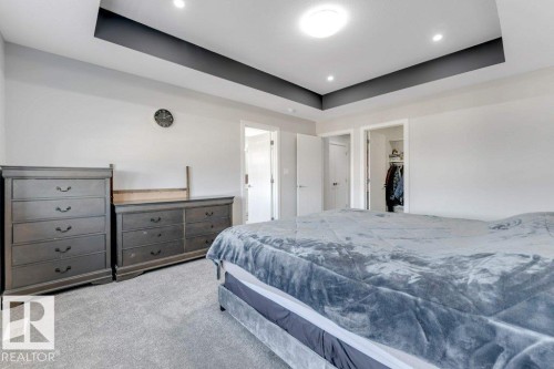 The property features a bedroom with a tray ceiling and recessed lighting, as well as soft gray carpeting - 452 Roberts Crescent, Leduc, AB - Indoor Photo Showing Bedroom