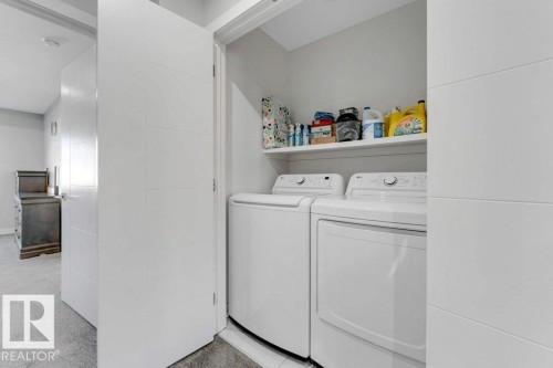 Dedicated laundry area featuring a white washer and dryer, with an overhead shelf for storage - 452 Roberts Crescent, Leduc, AB - Indoor Photo Showing Laundry Room
