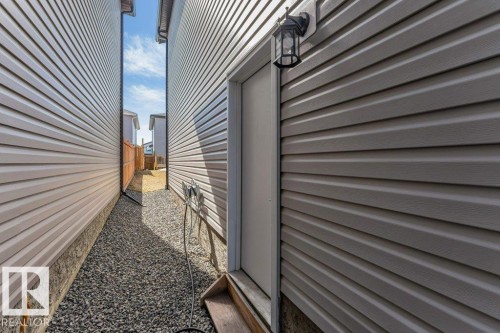 The exterior of the property features horizontal siding, a door with a wooden step, and a wall-mounted light fixture - 452 Roberts Crescent, Leduc, AB - Outdoor With Exterior