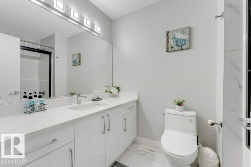 The bathroom features a spacious vanity with a white countertop and a large mirror - 452 Roberts Crescent, Leduc, AB - Indoor Photo Showing Bathroom