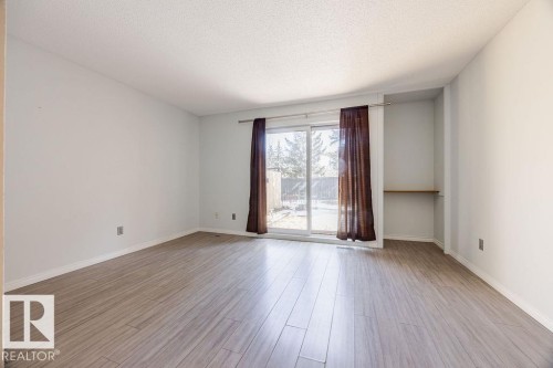 This bright interior space features light-toned laminate flooring, a newer sliding glass door to your lovely paving stone patio - 12032 25 Avenue, Edmonton, AB - Indoor Photo Showing Other Room