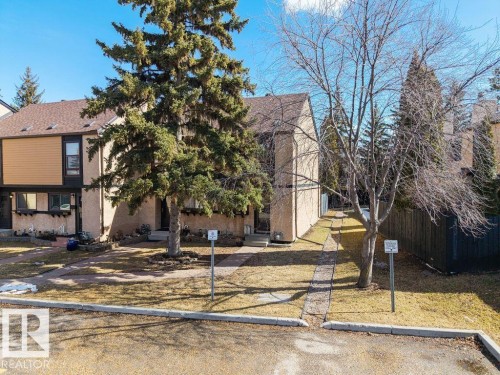 The property features a brown shingle roof, beige and brown exterior siding, and a paved walkway leading to the entrance - 12032 25 Avenue, Edmonton, AB - Outdoor