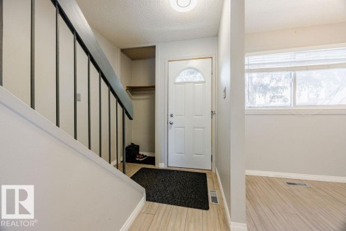 Inviting entryway with a white door featuring a decorative glass insert, light-colored flooring, and a built-in coat closet area - 12032 25 Avenue, Edmonton, AB - Indoor Photo Showing Other Room