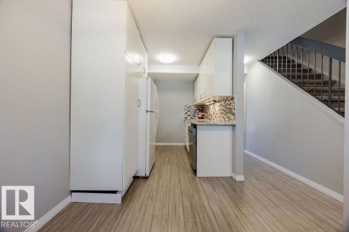 Kitchen area featuring granite countertops, stylish tile backsplash, upgraded sink, taps, and newer appliances. - 12032 25 Avenue, Edmonton, AB - Indoor Photo Showing Other Room