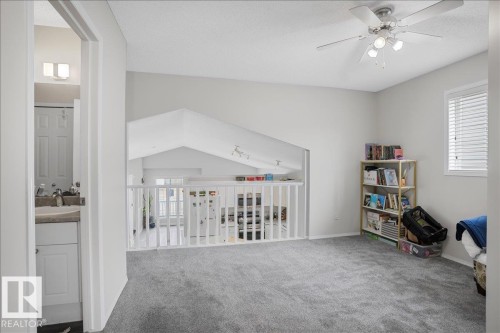 Bright open area with carpeted flooring, a ceiling fan, and a window with horizontal blinds - 3119 32 Avenue, Edmonton, AB - Indoor