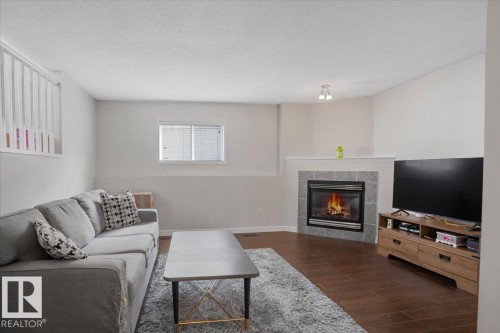 Living space featuring hardwood flooring and a corner fireplace with a tiled surround - 3119 32 Avenue, Edmonton, AB - Indoor Photo Showing Living Room With Fireplace