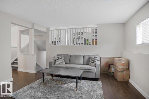 Living area featuring dark hardwood floors, light-colored walls, and a window with blinds - 3119 32 Avenue, Edmonton, AB - Indoor Photo Showing Living Room