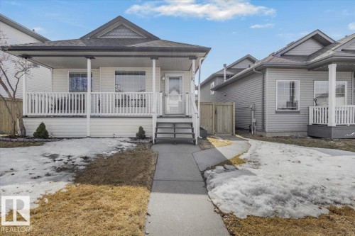 The property features a charming covered front porch with white railing, a grey shingle roof, and a paved walkway leading to the front entrance - 3119 32 Avenue, Edmonton, AB - Outdoor With Deck Patio Veranda With Facade