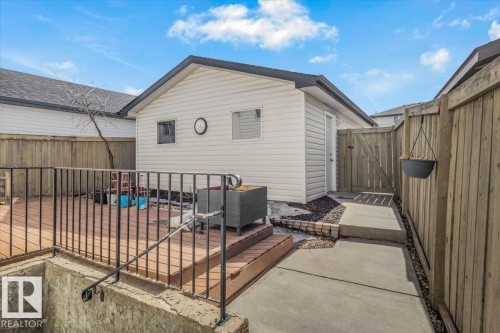 The property features a concrete patio area, a wooden deck with a black metal railing, and a wooden fence providing privacy - 3119 32 Avenue, Edmonton, AB - Outdoor With Exterior