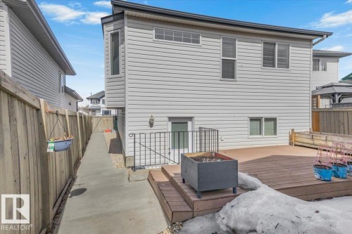 The property features light-colored siding, a multi-level wooden deck, and a walkway leading to the backyard - 3119 32 Avenue, Edmonton, AB - Outdoor With Deck Patio Veranda With Exterior