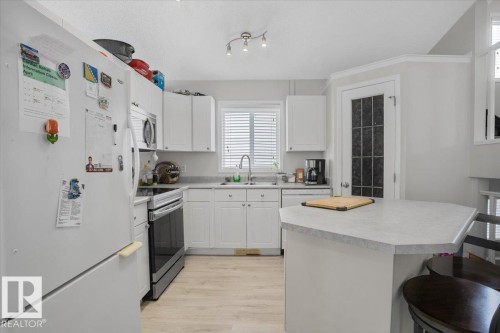 The kitchen features white cabinetry, light-colored countertops, and light wood tone flooring - 3119 32 Avenue, Edmonton, AB - Indoor Photo Showing Kitchen