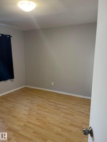 This room features light wood-style flooring, light-colored walls, and a ceiling-mounted light fixture - 10965 96 Street Nw, Edmonton, AB - Indoor Photo Showing Other Room