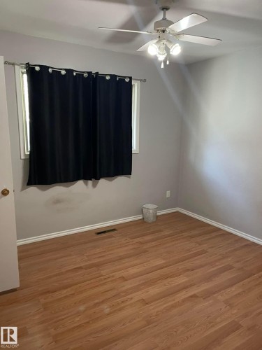 This room features wood-look flooring and a ceiling fan with integrated lighting - 10965 96 Street Nw, Edmonton, AB - Indoor Photo Showing Other Room