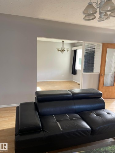 The property features an open floor plan with light-colored flooring and a chandelier in the dining area - 10965 96 Street Nw, Edmonton, AB - Indoor