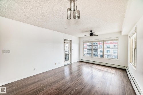 Spacious room featuring dark wood-style flooring, white walls, and a large window with blinds - 301 103 Ambleside Drive, Edmonton, AB - Indoor Photo Showing Other Room