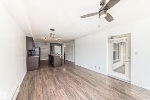 Open concept living area featuring wood-look flooring, a ceiling fan with integrated lighting, and a door leading to an exterior space - 301 103 Ambleside Drive, Edmonton, AB - Indoor