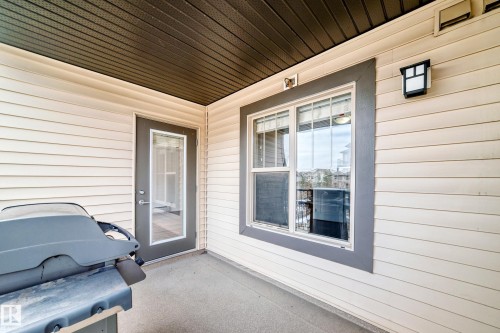 The property features a patio with a dark grey ceiling, beige siding, and a glass-paneled door - 301 103 Ambleside Drive, Edmonton, AB - Outdoor With Exterior