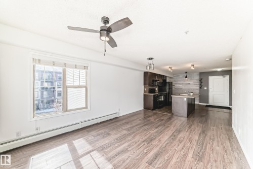 Open concept living space featuring hardwood floors, a ceiling fan with integrated lighting, and a window with blinds providing natural light - 301 103 Ambleside Drive, Edmonton, AB - Indoor