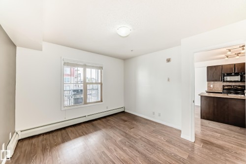 Living area featuring wood-look flooring, white walls, and a window with blinds - 301 103 Ambleside Drive, Edmonton, AB - Indoor