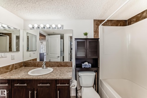 Bathroom featuring a vanity with a countertop and undermount sink, a large mirror with vanity lighting, and a bathtub with a shower - 301 103 Ambleside Drive, Edmonton, AB - Indoor Photo Showing Bathroom