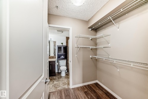 The property offers a walk-in closet with wire shelving, wood-style flooring, and a neutral wall color - 301 103 Ambleside Drive, Edmonton, AB - Indoor With Storage