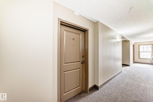 Hallway featuring a neutral color palette, wall sconces, and a window providing natural light - 301 103 Ambleside Drive, Edmonton, AB - Indoor Photo Showing Other Room