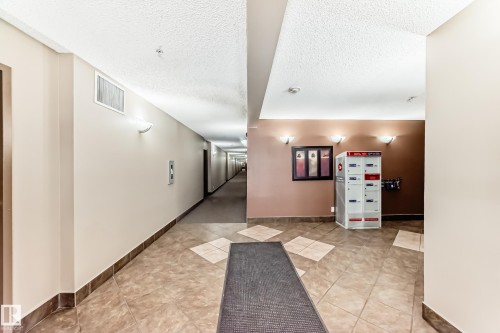 The property features a well-maintained common hallway with wall-mounted lighting and tiled flooring - 301 103 Ambleside Drive, Edmonton, AB - Indoor Photo Showing Other Room