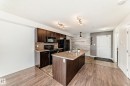 The kitchen features dark wood cabinetry, black appliances, and a central island with a granite-style countertop and an integrated sink - 301 103 Ambleside Drive, Edmonton, AB  - Indoor Photo Showing Kitchen 
