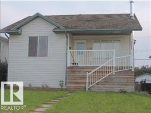 The property features a front lawn with a stone pathway, a wooden porch with white railings, and siding exterior - 1318 8 Avenue, Cold Lake, AB - Outdoor