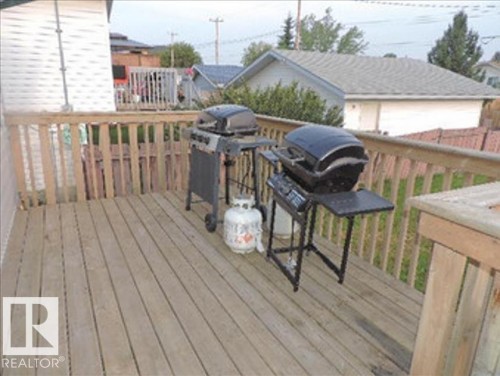 The property features a wooden deck with a wooden railing - 1318 8 Avenue, Cold Lake, AB - Outdoor With Deck Patio Veranda With Exterior