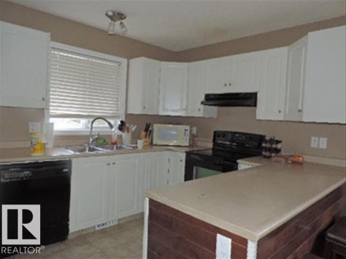The kitchen features white cabinetry, a double basin sink, and a dishwasher - 1318 8 Avenue, Cold Lake, AB - Indoor Photo Showing Kitchen With Double Sink