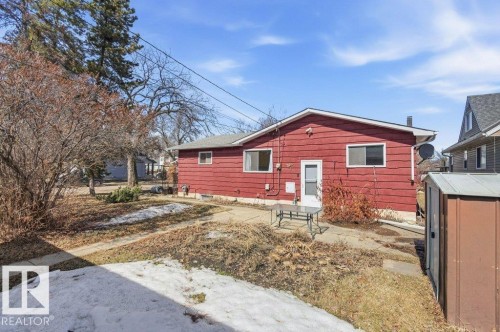 The property features red exterior siding, a white entry door, and multiple windows - 10459 66 Avenue, Edmonton, AB - Outdoor With Exterior