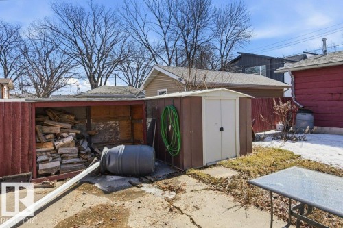 The property features a storage shed with a brown and white exterior, and a separate covered wood storage area - 10459 66 Avenue, Edmonton, AB - Outdoor