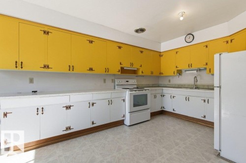 The kitchen features white base cabinets, yellow upper cabinets, and a white refrigerator - 10459 66 Avenue, Edmonton, AB - Indoor Photo Showing Kitchen