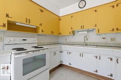 The kitchen features extensive cabinetry with yellow upper cabinets and white lower cabinets, a white electric range, and a sink with a gooseneck faucet - 