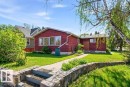 The property features a stone retaining wall and steps leading to a pathway, a vibrant green lawn, and mature trees - 10459 66 Avenue, Edmonton, AB  - Outdoor 