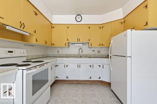 The kitchen features white appliances, including a range and a refrigerator, complemented by yellow and white cabinetry - 10459 66 Avenue, Edmonton, AB - Indoor Photo Showing Kitchen