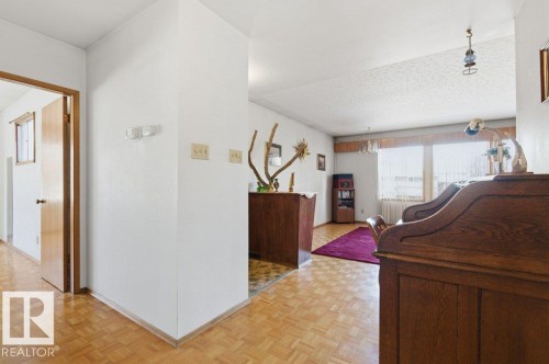 The interior features patterned wood flooring throughout, with a contrasting purple area rug in one section - 10459 66 Avenue, Edmonton, AB - Indoor