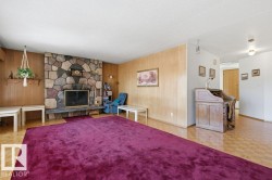 Living room featuring a natural stone fireplace, hardwood floors, and wood paneling - 