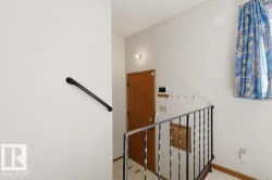 The property features a staircase with a wrought iron railing, a wooden door, and a wall-mounted handrail - 