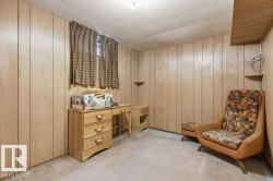 The room features light-toned wood paneling on the walls and a window with patterned curtains - 