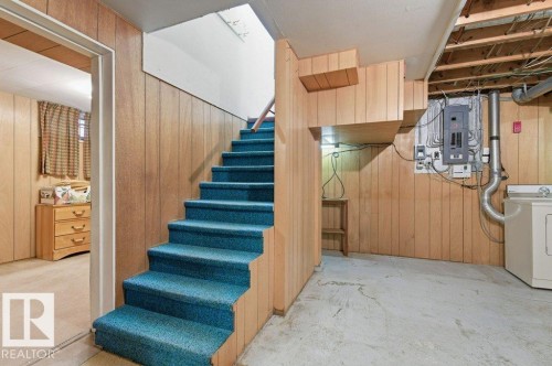 A staircase with blue carpet leads to a finished area with wood paneling - 10459 66 Avenue, Edmonton, AB - Indoor