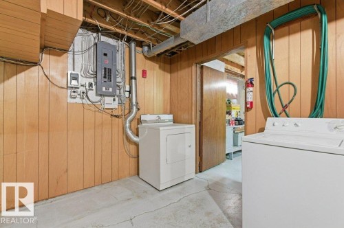 Laundry area featuring a washer and dryer, wood paneling, and exposed ceiling joists - 10459 66 Avenue, Edmonton, AB - Indoor Photo Showing Laundry Room
