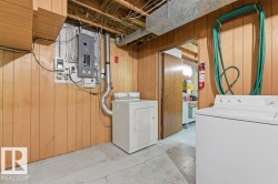 Laundry area featuring a washer and dryer, wood paneling, and exposed ceiling joists - 