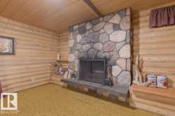 Living area featuring a stone fireplace with a metal screen, wood paneled walls, and a wood ceiling - 