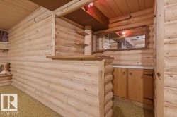 This space features extensive wood paneling and a built-in bar area with a wooden countertop and shelving - 