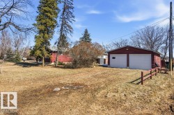 The property includes a spacious yard with a detached two-car garage featuring white garage doors - 